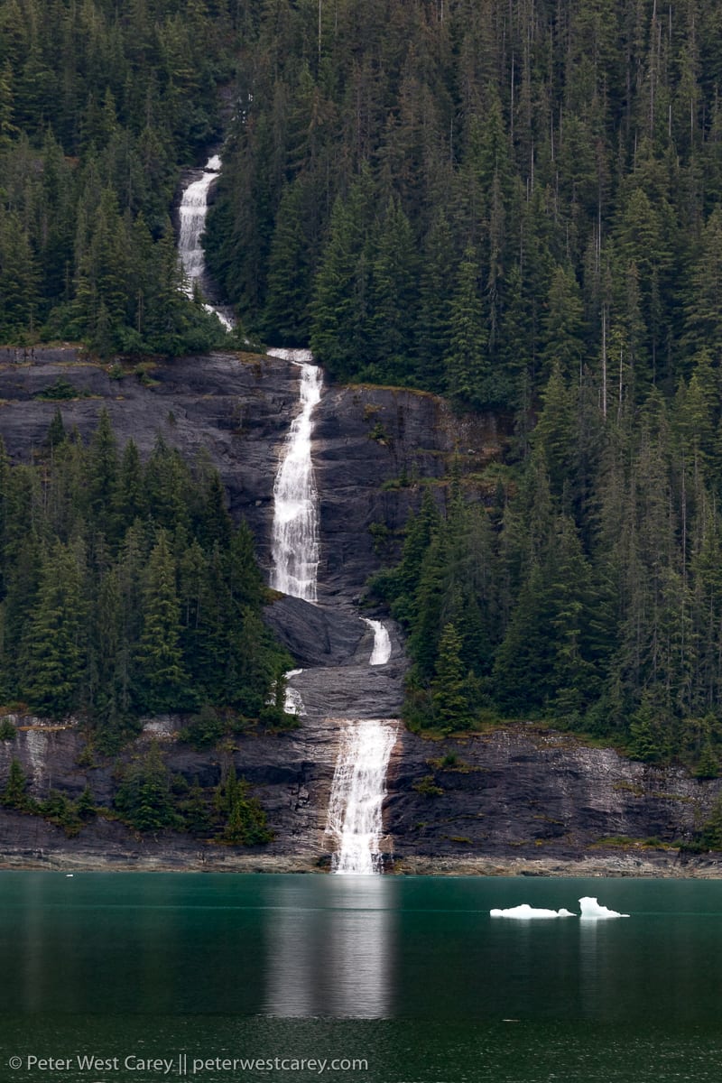 A waterfall in Alaska plummets to the icy waters of a bay